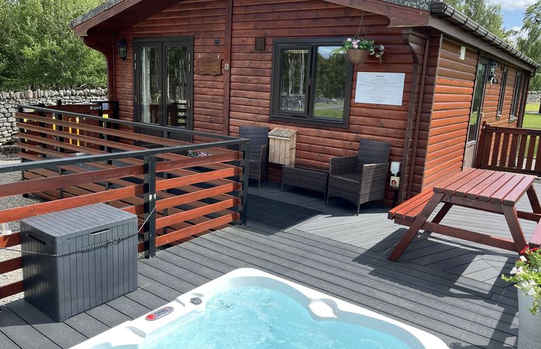 An outdoor area with a deck, spa, and seating at Wildcat Lodge in Newtonmore