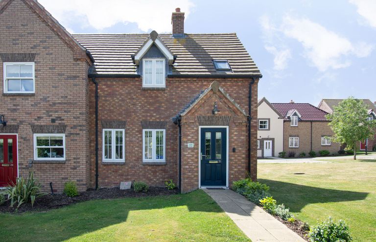 A brick house with a blue front door and white windows with a garden and pathway in front at Lilipad Cottage The Bay near Filey