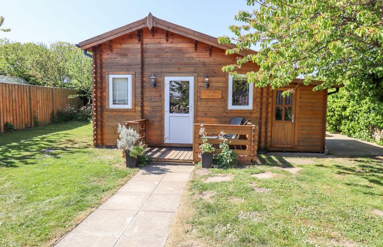 A wooden cabin with a small porch and garden path at Aurora Skies in Cresswell near Morpeth