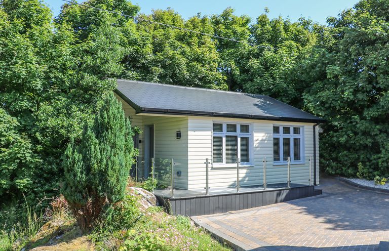 A small house with a glass railing and driveway surrounded by trees at Hidden Gem Cabin in Lettermacaward near Dungloe County Donegal