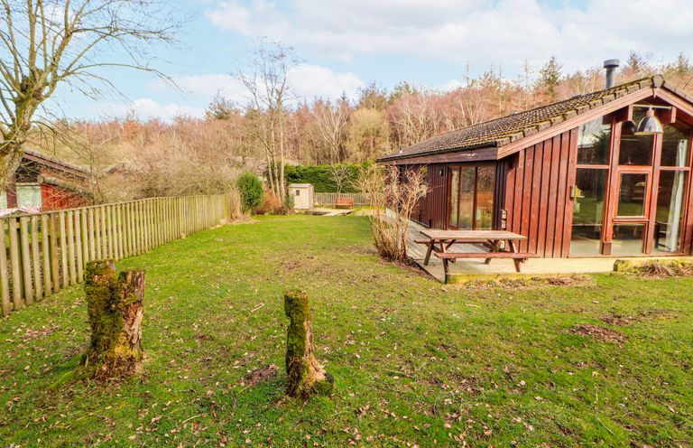 A garden with a wooden house and table at 26 Dukes Meadow Greystoke near Penrith
