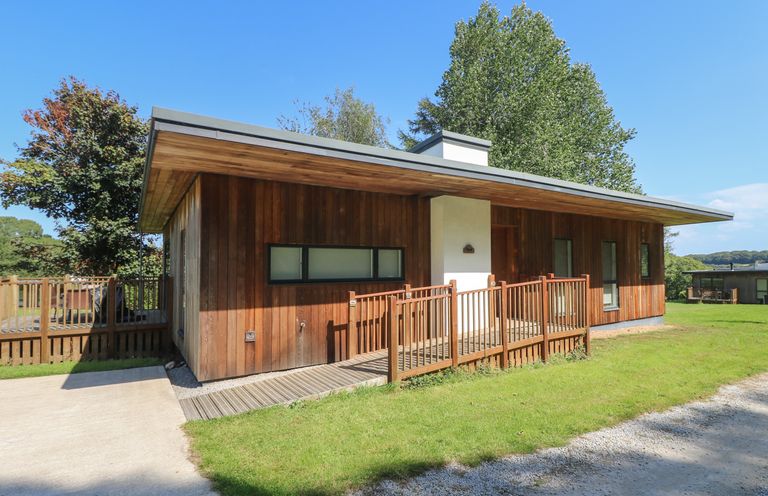 A wooden cabin with a ramp and railing on a lawn under a clear blue sky at Beech in Truro