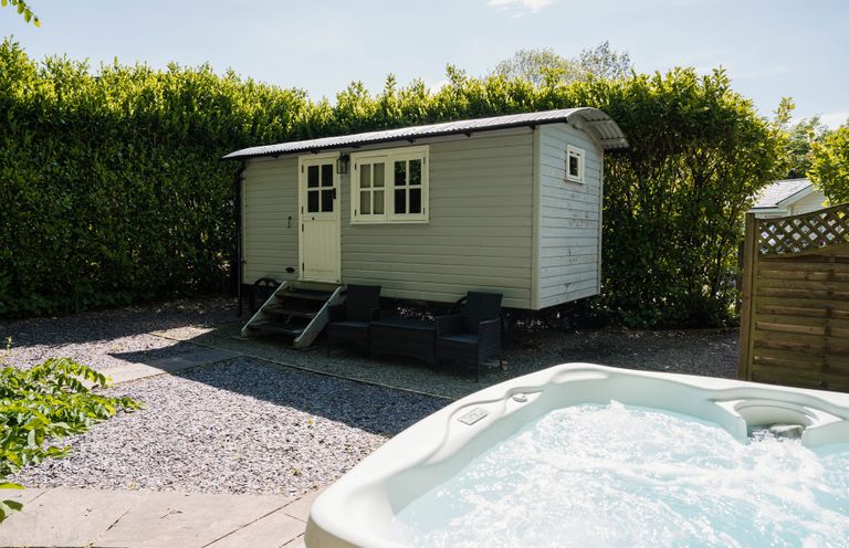 A hot tub and a cabin in a garden area at The Snug in Longtown