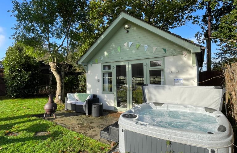 An outdoor patio with a hot tub sofa and a small fireplace outside a cottage at Pheasant Lodge in Wimborne Minster