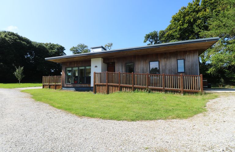 A single story wooden house with large windows and a gravel driveway at Elm in Truro