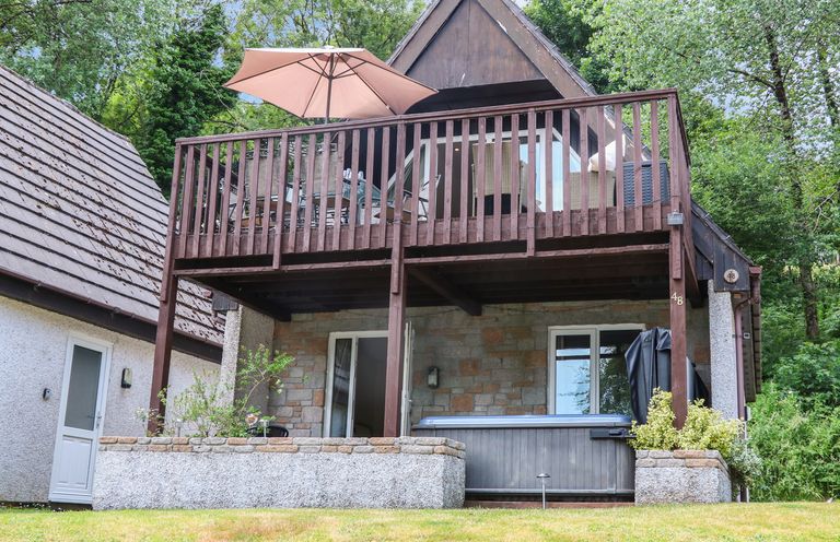 A two story house with wooden balcony and patio area with hot tub and outdoor furniture at Valley Lodge 48 in Callington