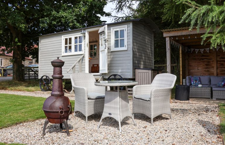 An outdoor seating area with a table and two chairs next to a small shed and a covered seating area at Bellwether in Helmsley