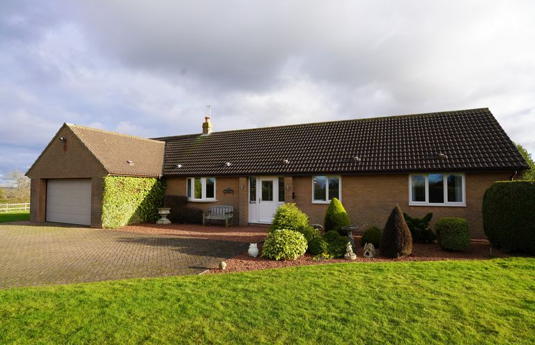 A single-story brick house with a tiled roof lawn and bushes in front at Holly Edge in Moorsholm