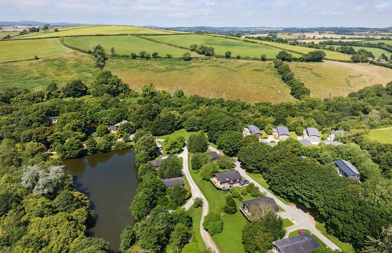 A countryside area with houses near a pond surrounded by trees and fields at 9 Stonerush Valley in Lanreath