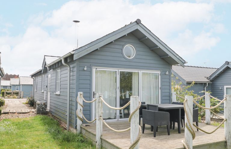 A wooden cabin with a small deck and outdoor table and chairs at Sea Breeze The Bay near Filey